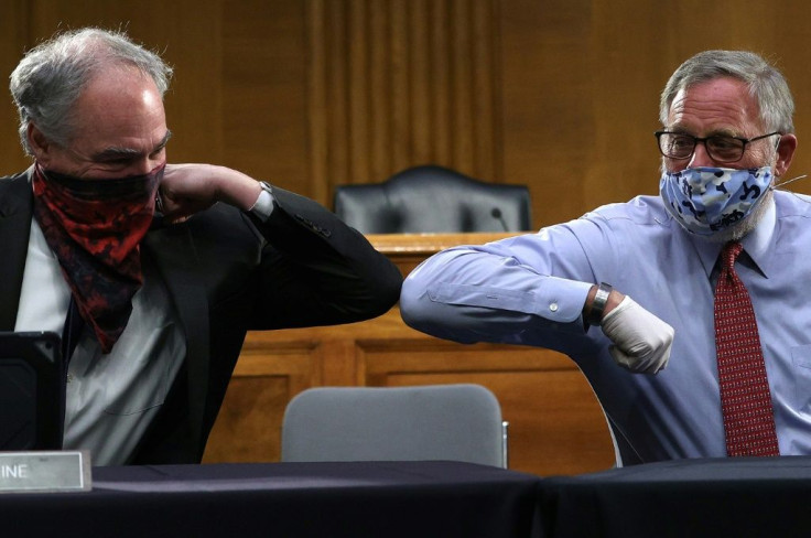 US Senators Tim Kaine (L) and Richard Burr greet each other with an elbow bump before a Senate committee hearing on the coronavirus epidemic
