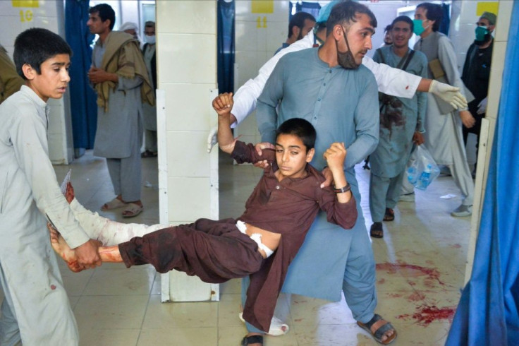 Volunteers carry a wounded boy into a hospital following the suicide attack on the funeral of a local police commander in Nangarhar on May 12, 2020