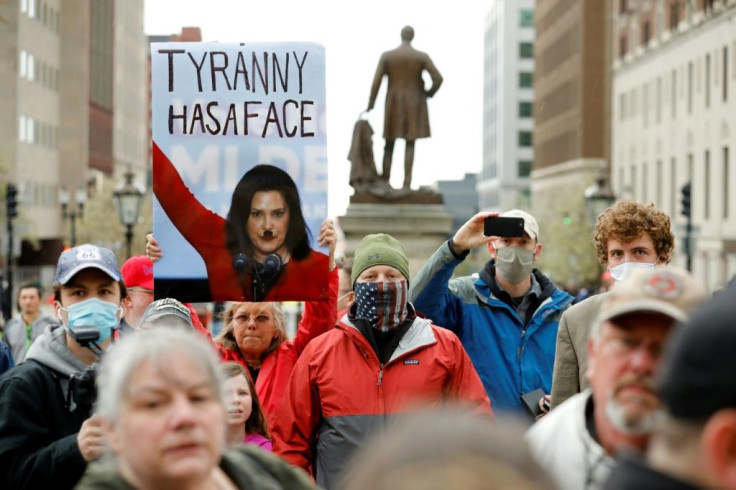 A Hitler moustache drawn on a picture of Michigan Governor Gretchen Whitmer on a sign held by a protestor at an anti-lockdown demonstration in Lansing, Michigan