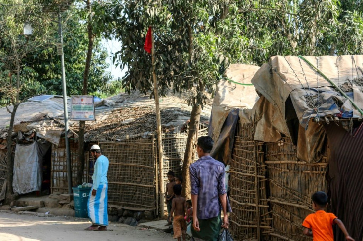 Rohingya refugees walk past a red flag used to mark the house of a resident infected with coronavirus in a sprawling camp on the Bangladesh-Myanmar border housing nearly a million people