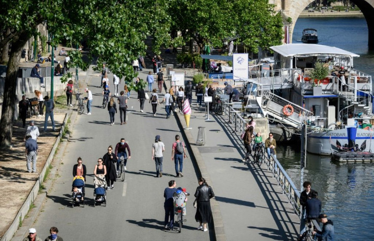 People walk on the banks of the Seine River in Paris on May 15 as France eases lockdown measures taken to curb the spread of the COVID-19 pandemic