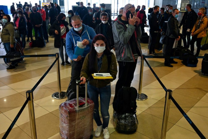 Ukrainian seasonal workers wait in line to check in for a flight to Finland where they can earn much more than at home as the coronavirus pandemic ravages the economy