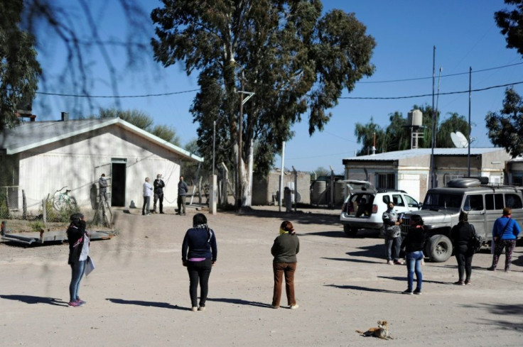 Mothers maintain a safe distance as they queue for educational material and food bags for their children outside a school in El Retamo