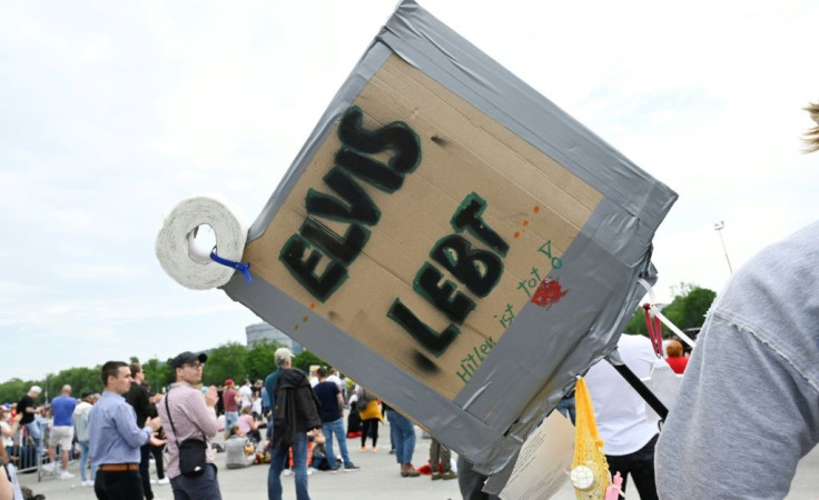 A demonstrator holds a placard that reads 'Elvis is alive' at a protest in Stuttgart