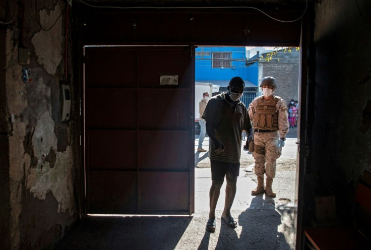 A soldier asks a Haitian migrant to enter his home so that it is sanitized by municipal workers at a low-income area in Santiago, amid mandatory total quarantine due to COVID-19