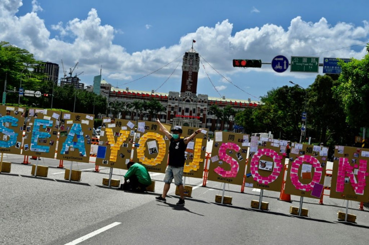 A man poses for photos in front of a 'Lennon Wall' next to the Presidential Office in Taipei