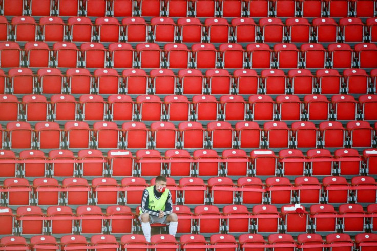 A Bayern Munich substitute player wearing a protective face mask maintains social distance in the stands during a match against FC Union Berlin played without fans