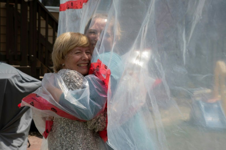 A plastic-covered hug will never be as good as the real thing, but Carolyn Ellis (R) said the "hug glove" she and her husband made helps things "kind of get back to normal"