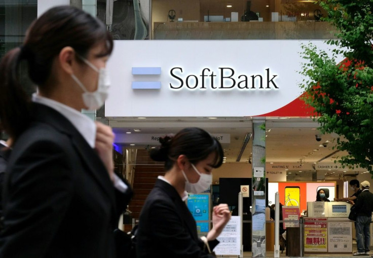 Pedestrians walk past a SoftBank mobile shop in Tokyo on the day the parent conglomerate announced a $8.9 billion annual net loss