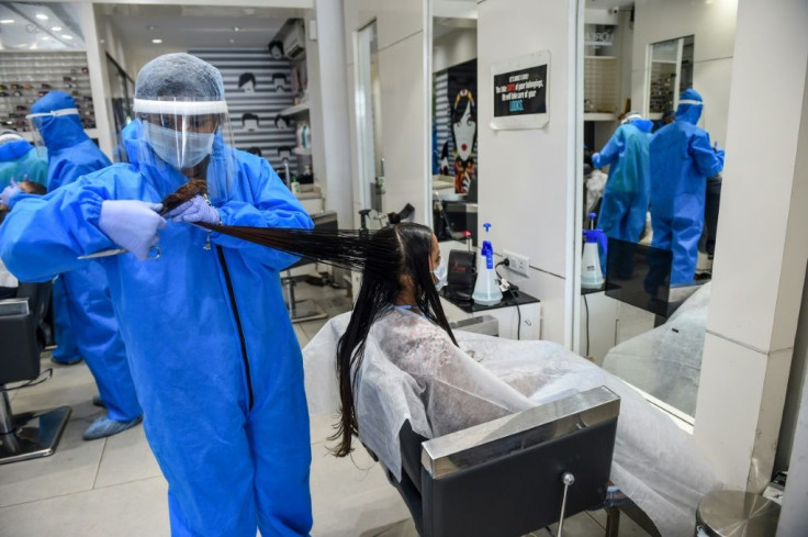 A hairdresser in protective gear attends to a customer at a hair and beauty salon in Nadiad, nearAhmedabad, India