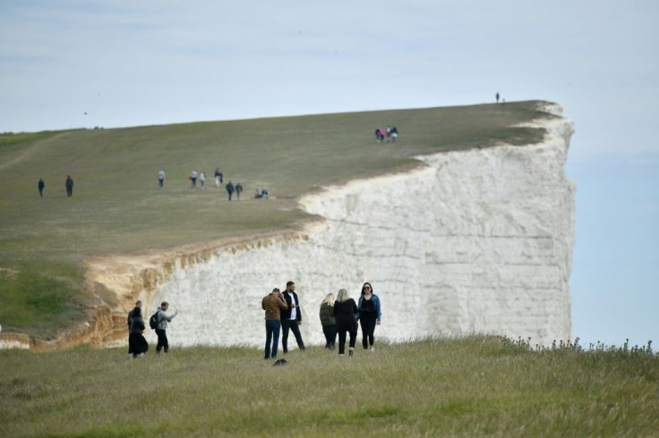 People pose for photographs on the cliff-edge at Beachy Head near Eastbourne following an easing of lockdown rules in England