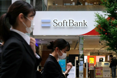 Pedestrians walk past a SoftBank mobile shop in Tokyo on the day the parent conglomerate announced a $8.9 billion annual net loss