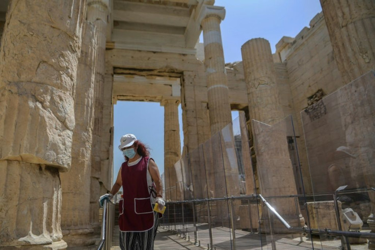 A worker wearing a protective mask cleans the entrance of the Acropolis