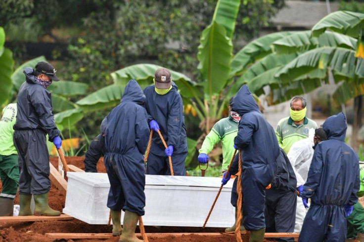 Gravediggers lower the coffin of a  COVID-19 victim into a grave at Pondok Ranggon cemetery in Jakarta