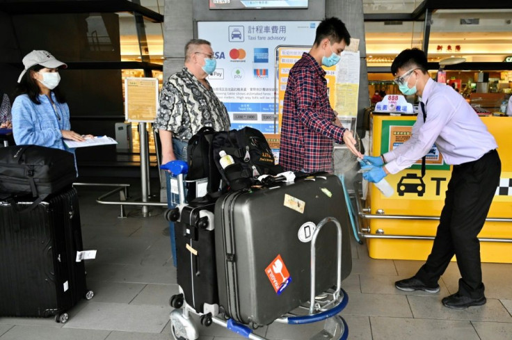 A worker sprays sprays hand sanitizer onto passengers after they arrive at Taoyuan Airport near Taipei in March 2020 amid the COVID-19 pandemic