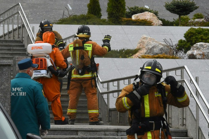 Emergency personnel wearing protective gear spray disinfectant on colleagues at the site of a fire linked to ventilators at the Saint George hospital in Saint Petersburg on May 12, 2020