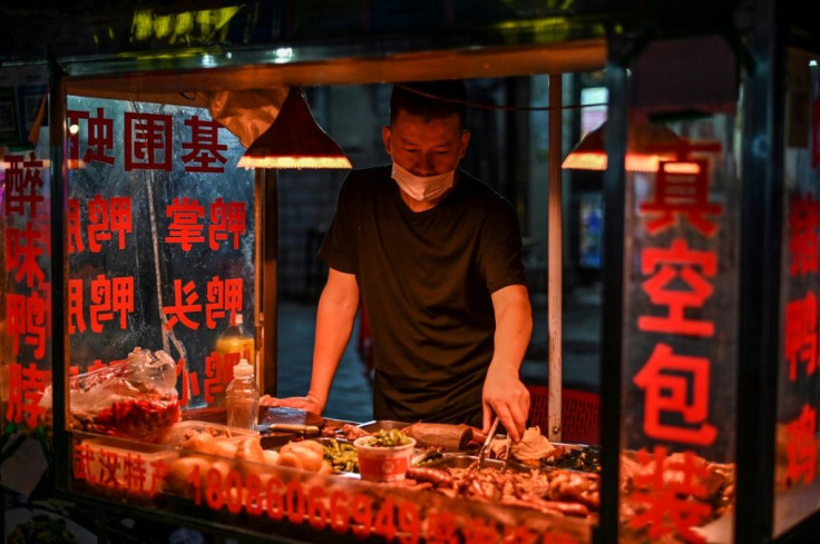 A man wearing a facemask sells food at his stall on a street in Wuhan, China