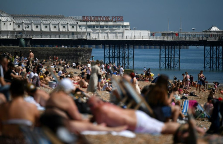 People enjoy the sunshine on the beach in Brighton, on the south coast of England, as the country's official coronavirus death toll rose to 25,079
