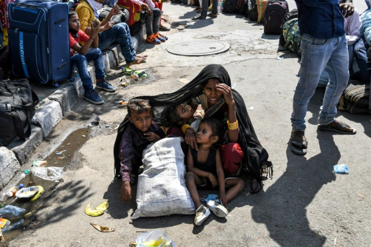 A woman covers her children with a shawl to protect them from the sun as she waits in New Delhi with other migrant workers and families to get registered for travel to their home towns after the goverment eased its nationwide lockdown