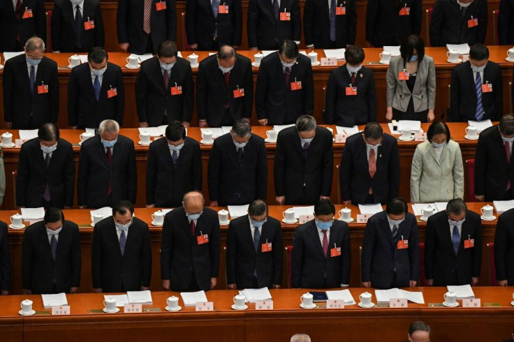 Delegates wearing face masks stand in a silent tribute for victims of the COVID-19 coronavirus during the opening session of the National People's Congress (NPC) at the Great Hall of the People in Beijing