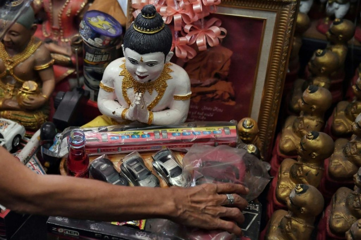 Fizzy sodas, giant lollipops, and toy planes and cars are placed as offerings to the 'Golden Son' dolls in Thailand