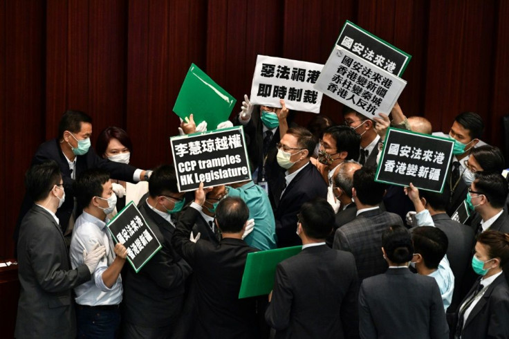 Hong Kong pro-democracy lawmakers holding up placards are blocked by security as they protest China's planned national security legislation during a House Committee meeting