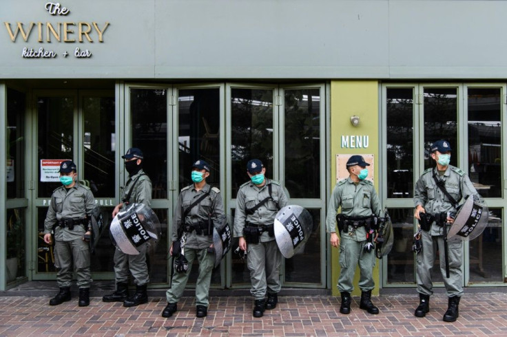 Riot police stand guard near a group of pro-democracy protesters in Hong Kong, who are stopped for breaking restrictions on social distancing during the coronavirus pandemic