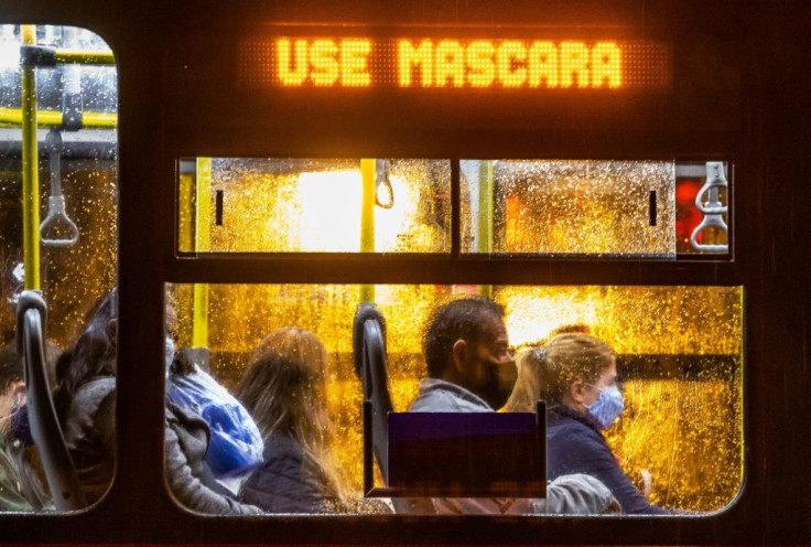 Commuters wearing face masks travel on a public bus with an electronic sign reading "Wear a face mask", in Curitiba, Brazil on May 22, 2020