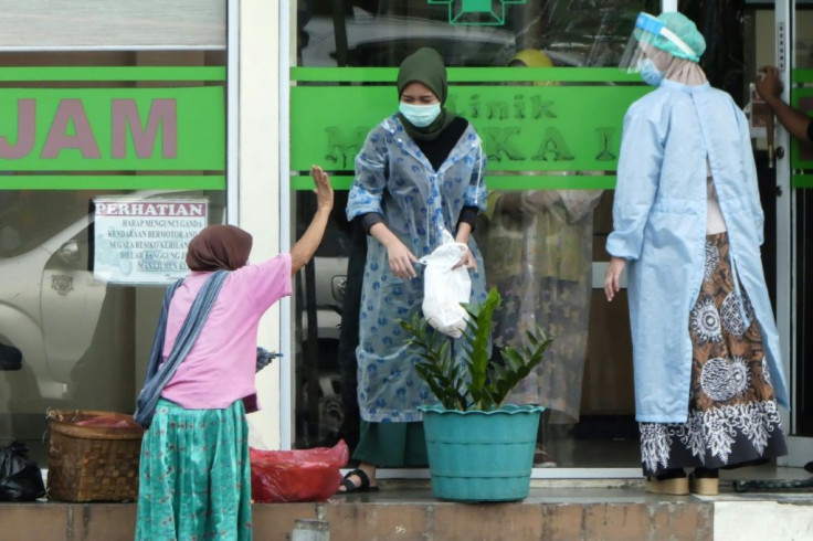 A food seller (L) gestures to health officials at a clinic in the Indonesian capital Jakarta