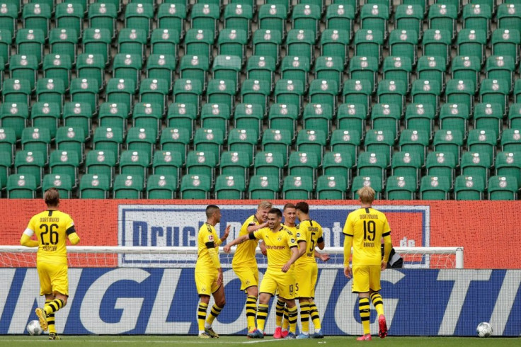 Raphael Guerreiro (C) celebrates scoring the opening goal in Borussia Dortmund's 2-0 win at Wolfsburg in a near-empty stadium.