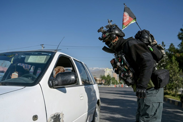An Afghan security forces member stops motorists at a checkpoint in Kabul at the start of the Eid al-Fitr festival