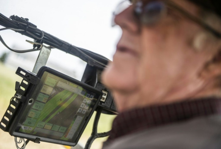 Dave Burrier uses a GPS readout to plant corn in even rows and ensure the entire field is covered in seeds