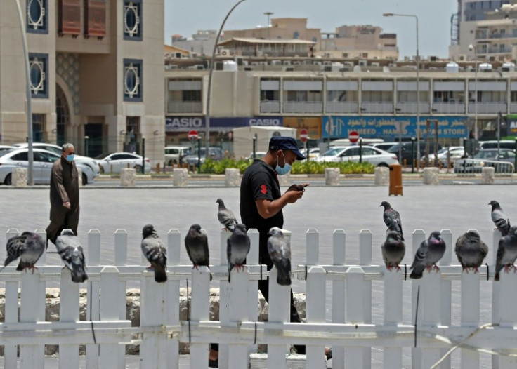 A masked man checks his phone in Qatar where residents and citizens have been required by law to install a coronavirus contact tracing app on their handsets since Friday