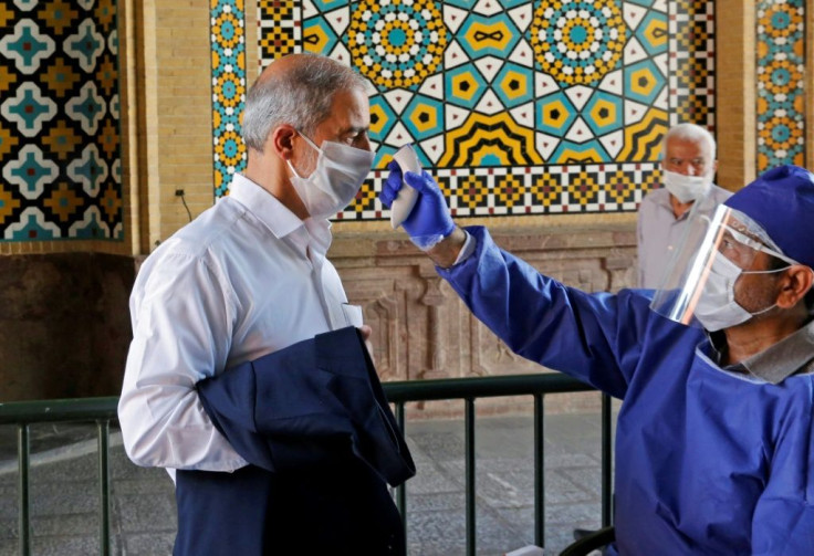 An Iranian official checks the temperature of visitors at the Shah Abdol-Azim shrine in the capital Tehran with strick health guidelines