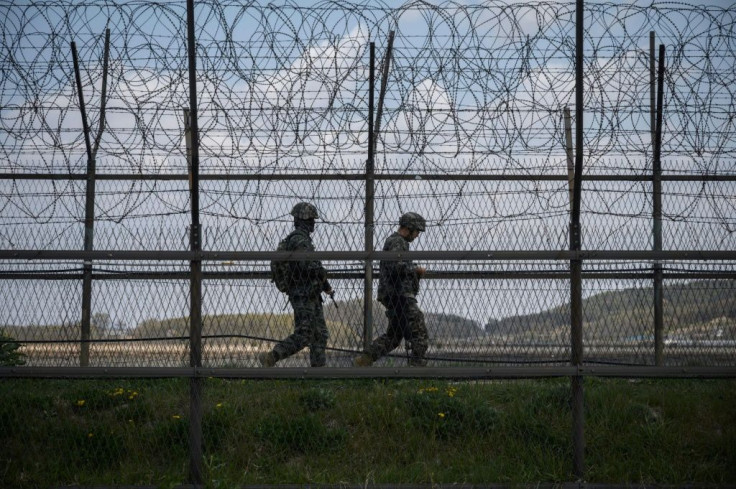 South Korean soldiers patrolling along a barbed wire fence at the  Demilitarized Zone with North Korea