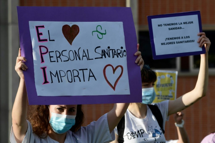 A healthcare worker in Spain holds a sign reading "Healthcare workers matter"