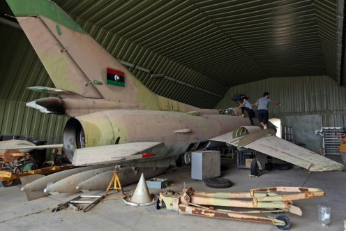 Fighters loyal to Libya's UN-recognised Government of National Accord (GNA) climb over a partially disassembled MiG 23 aircraft, after seizing Al-Watiya airbase  southwest of the capital Tripoli, on May 18, 2020.