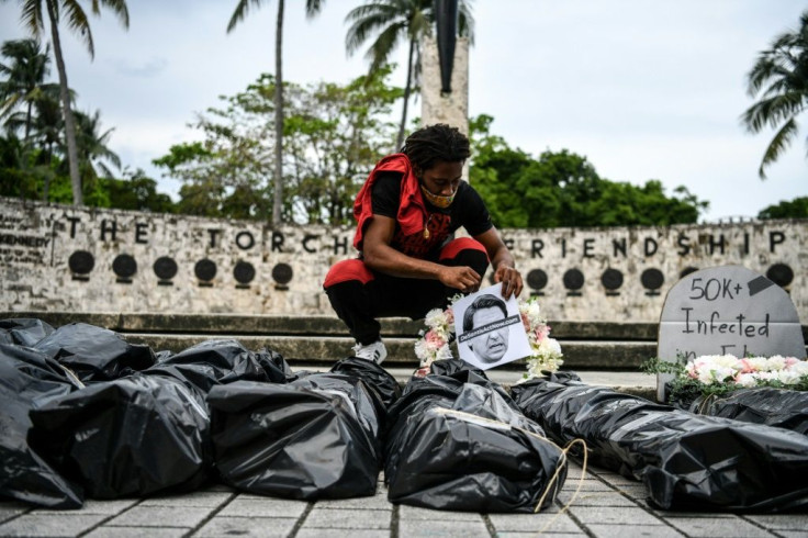 A protester sets up bags representing dead bodies during a funeral procession demonstration against the reopening of Florida, in Miami