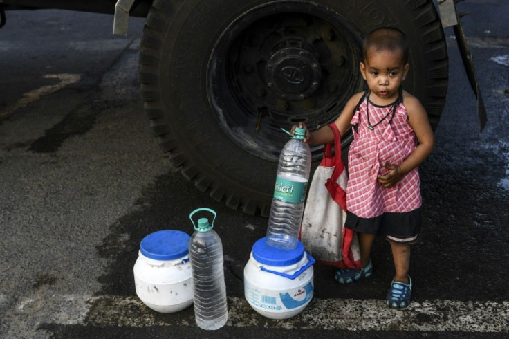 A child stands next to bottles and cans as her mother collects water from a tanker in New Delhi as the Indian government eases a nationwide lockdown