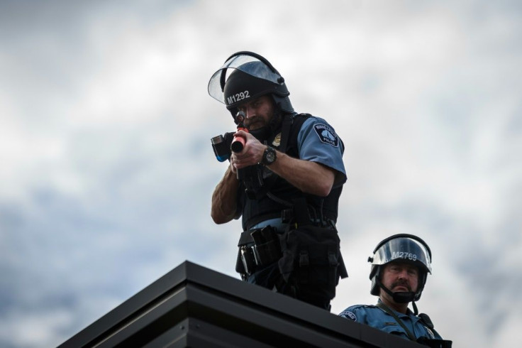 Two police officers stand on the roof of the Third Police Precinct holding a projectile launcher during a demonstration against the death of George Floyd, in Minneapolis, Minnesota on May 27, 2020