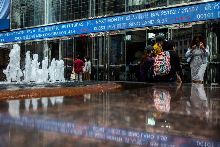 An electronic ticker board displays stock prices as mask-clad people gather by a fountain at Exchange Square in Hong Kong in March 2020