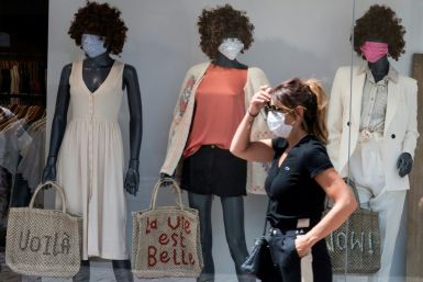 A woman wearing a face mask passes by a show window with masked mannequins in Mulhouse, eastern France