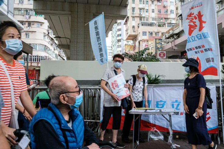 People stand at a booth where passersby can give their signatures in support of a new security law in Hong Kong