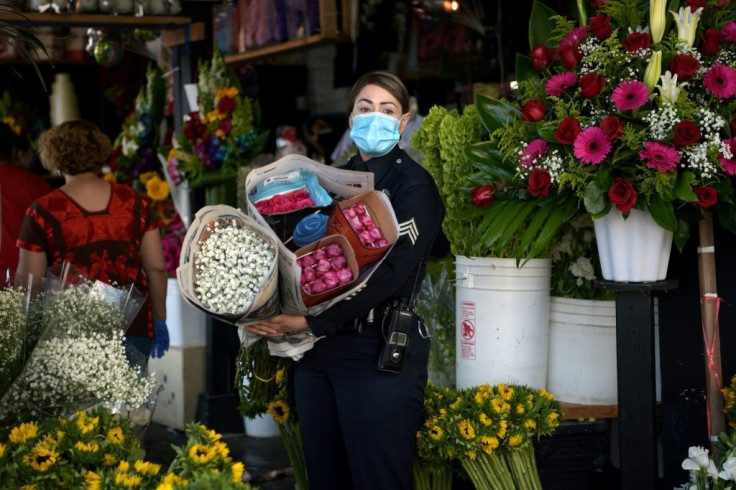 Los Angeles restaurants and hair salons were allowed to reopen; pictured is a May 8, 2020 file image of a policewoman shopping at LA's Flower District