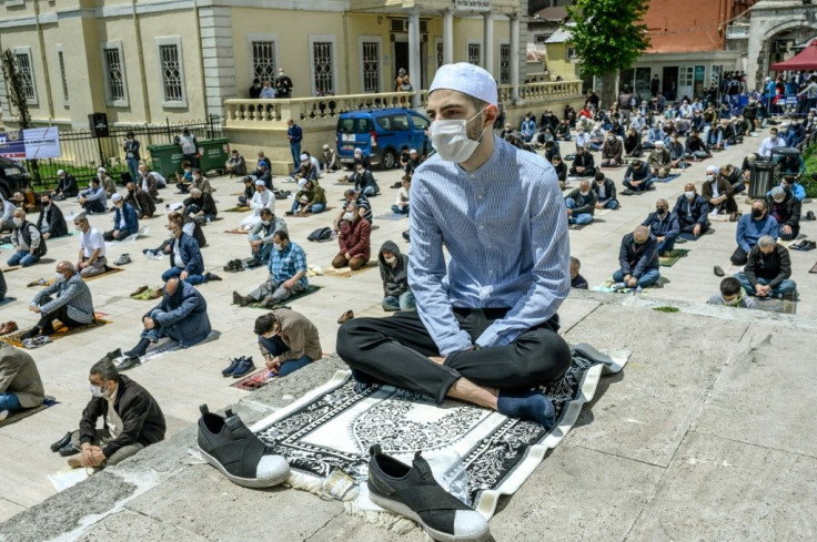 Worshippers wearing face masks maintain the required social distance during Friday prayers outside the reopened Fatih Mosque in Istanbul