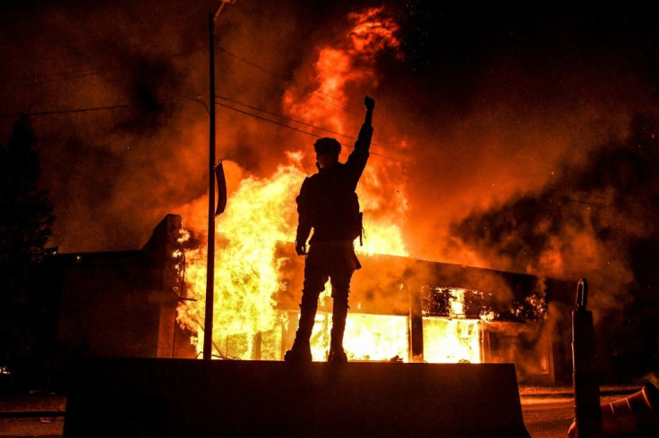 Un manifestant devant un bÃ¢timent incendie dans la ville amÃ©ricaine de Minneapolis dans la nuit du 29 au 30 mai 2020