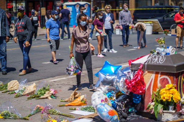 A woman brings flowers to a memorial for George Floyd, who died while in custody of the Minneapolis police, following a night of rioting