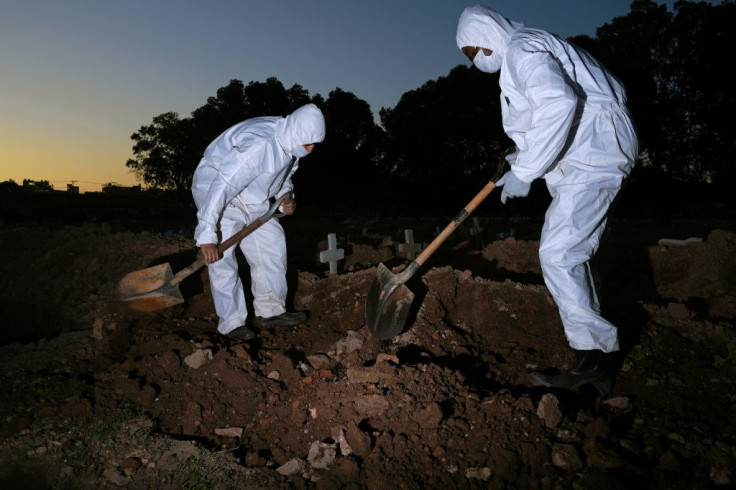 Workers wear protective clothing to bury a COVID-19 victim at the Sao Franciso Xavier cemetery in Rio de Janeiro, Brazil on May 29, 2020