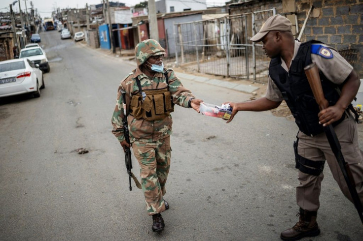 A South African soldier (left) hands over cigarettes he seized from a small shop to a policeman. The tobacco ban is still in force