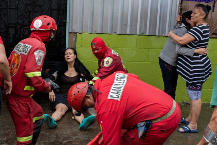 Members of a volunteer stretcher corps prepare to carry out a woman who fainted in an area flooded by Tropical Storm Amanda in San Salvador's Modelo neighborhood